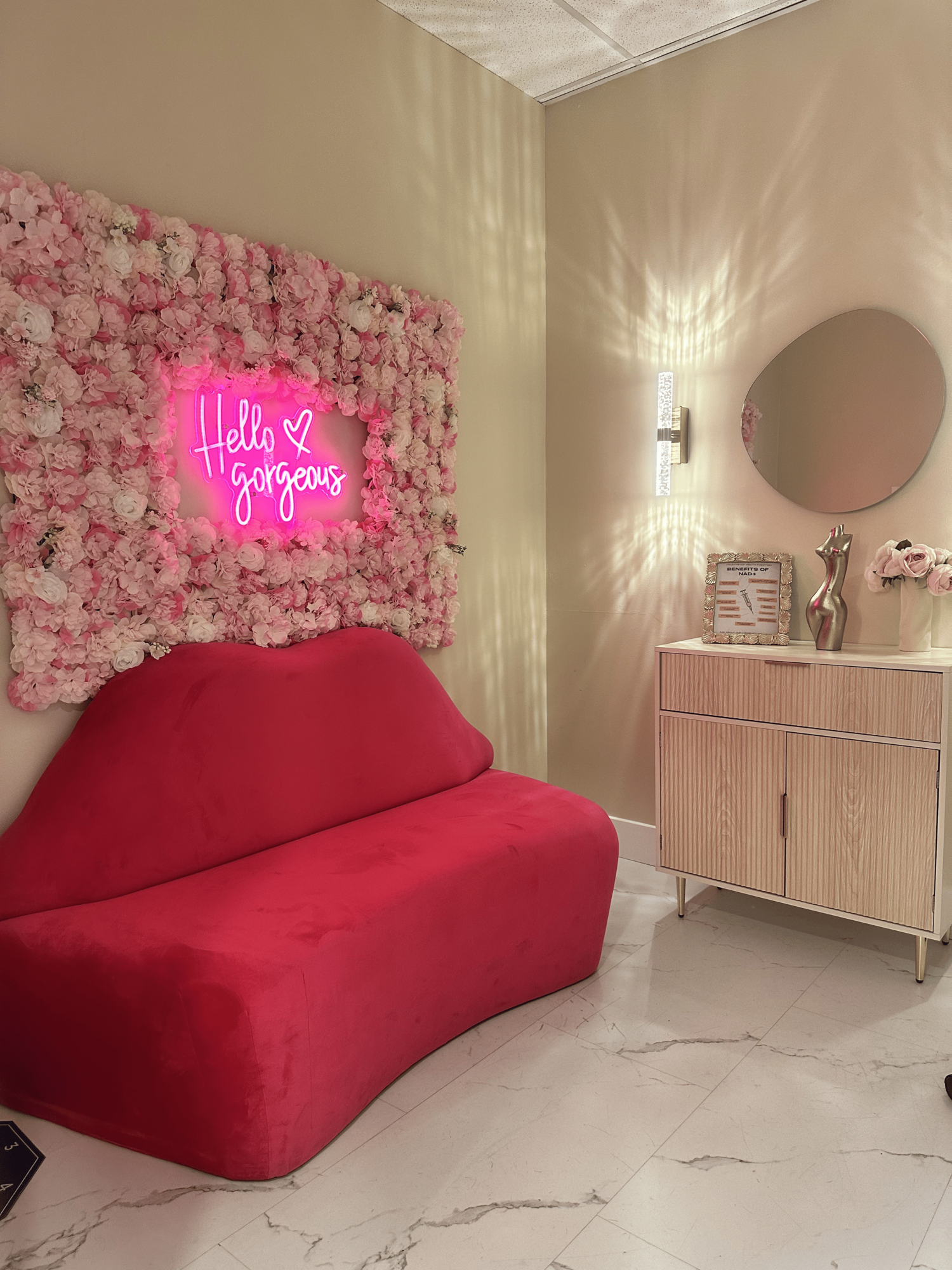 Total Body Aesthetic Hello Gorgeous neon sign with flower wall and lip sofa — Westchester Los Angeles medspa